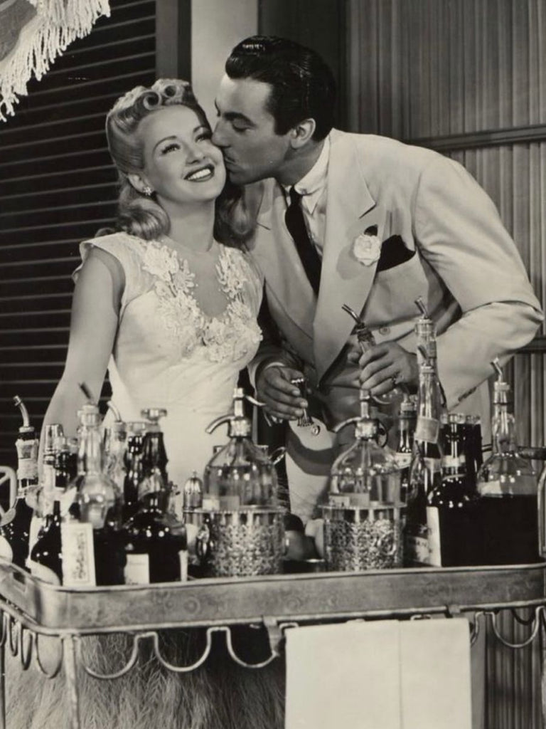 a man kisses a woman on the cheek, preparing a drink, black and white photo, from the 1930s