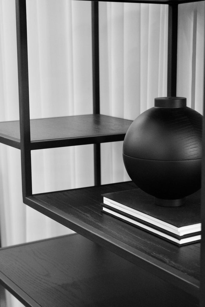 black wooden vase displayed on a metal shelving unit