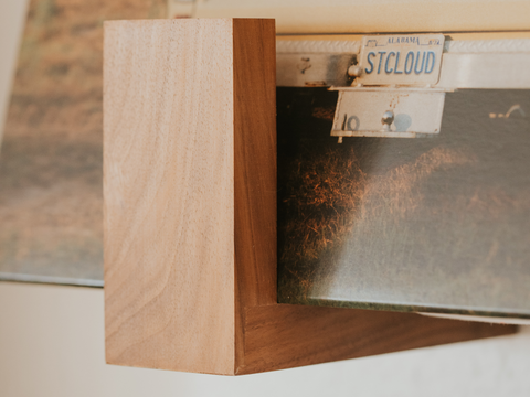 A close up of a walnut Flip Record Display Shelf holding and displaying records on the wall