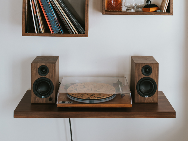 U-Turn Orbit Special turntable on a walnut base with U-Turn Ethos speakers in walnut on a Floating Record Player Table under a Wall Cube shelf filled with records