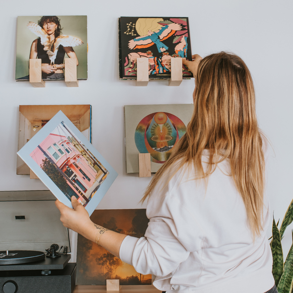 Blonde woman holding a record and placing another in a Flip Record Display Shelf to display it
