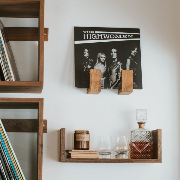 The Highwomen's record displayed on the wall in a set of Flip Record Display Shelves above a Floating U Shelf and next to two Wall Cubes all in walnut