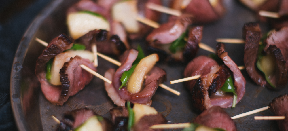 bites of duck meat with apple slices and basil leaves