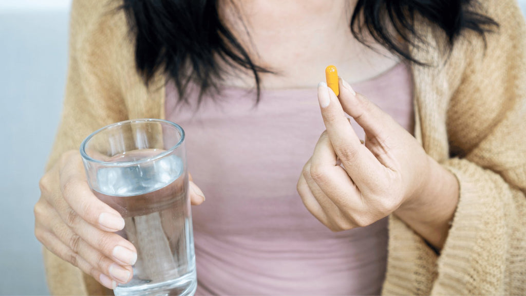 Woman consuming Berberine Capsule with a glass of water.