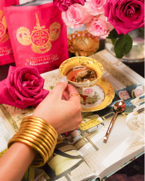 Woman Holding Yellow Tea Cup While Wearing Gold All Weather Bangle Bracelets Filled with BuDhaGirl Organic Tea | BuDhaGirl Teas and Tisanes