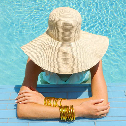 Model trägt Gold All Weather Bangles im Schwimmbad