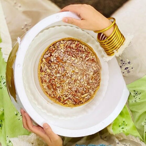 Hands wearing BuDhaGirl Gold All Weather Bangles and holding sweet dish for Eid 2021 | BuDhaGirl