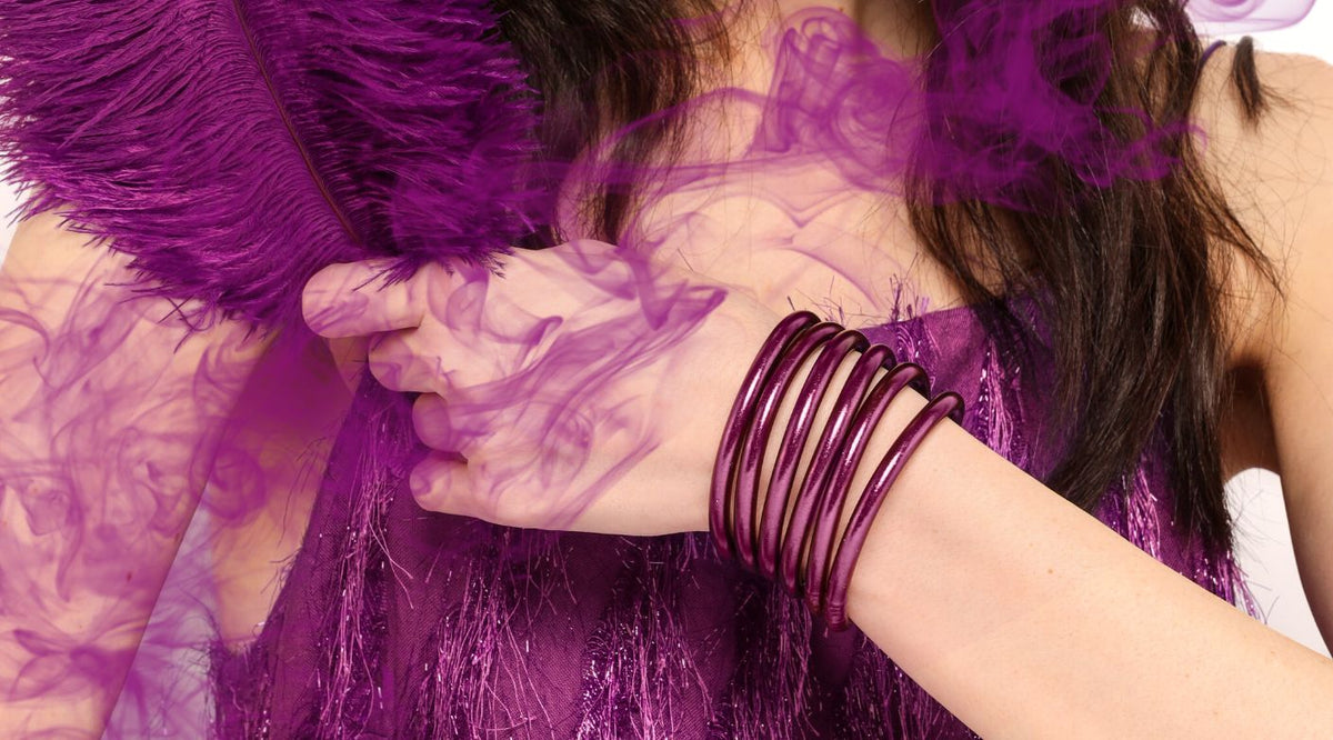 Femme en robe violette tenant une plume violette portant BuDhaGirl Amethyste violet All Weather Bangles | Budhabrief par BuDhaGirl 