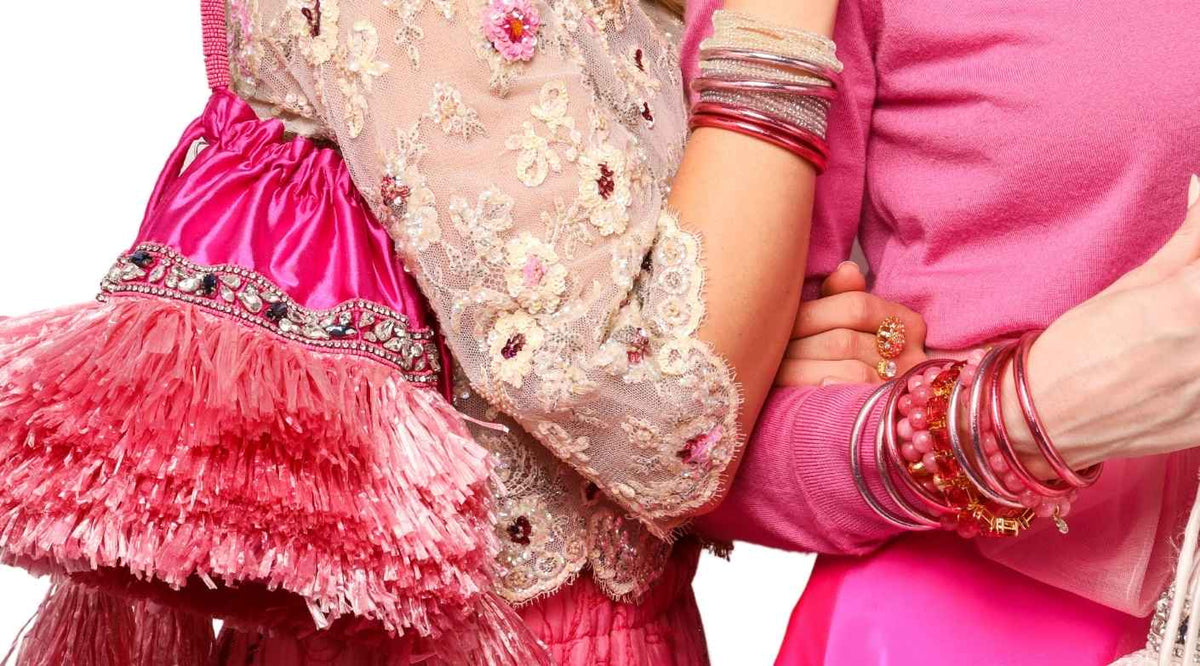 Two women wearing BuDhaGirl's Carousel Pink Collection, All Weather Bangles in Carousel Pink, Bianca beaded bracelets in Peony, Pink and Petal, Dahlia Bracelet in Peony, Meghan 5 strand Crystal bracelets in Pink and Clear, BuDhaGirl's Lola Raffia Bag In Carousel Pink | BuDhaBrief by BuDhaGirl