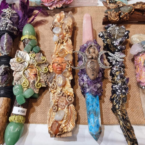Four crystal spiritually divine wands laying flat on a white table. Handmade with gemstones and clay.