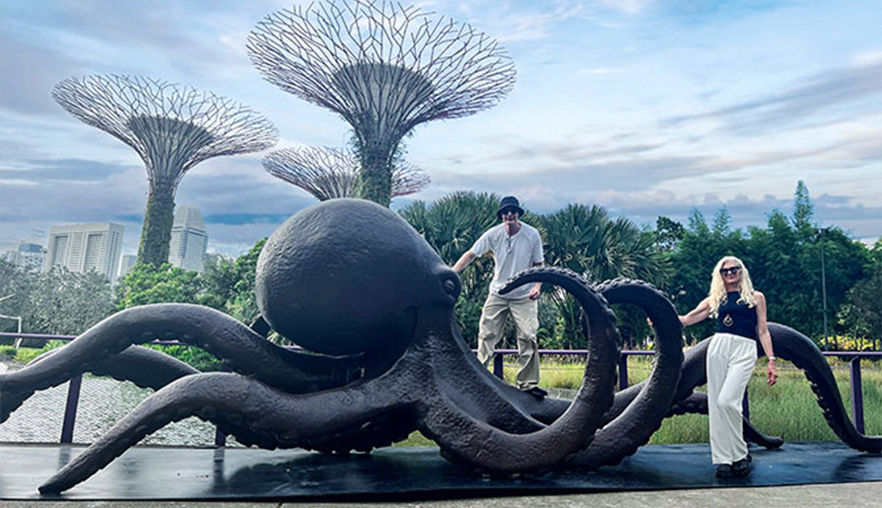 Artist duo Gillie and Marc stood next to giant life size bronze sculpture of Octopus in Singapore