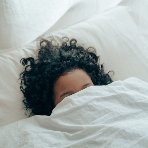 Woman sleeping in bed with her face covered