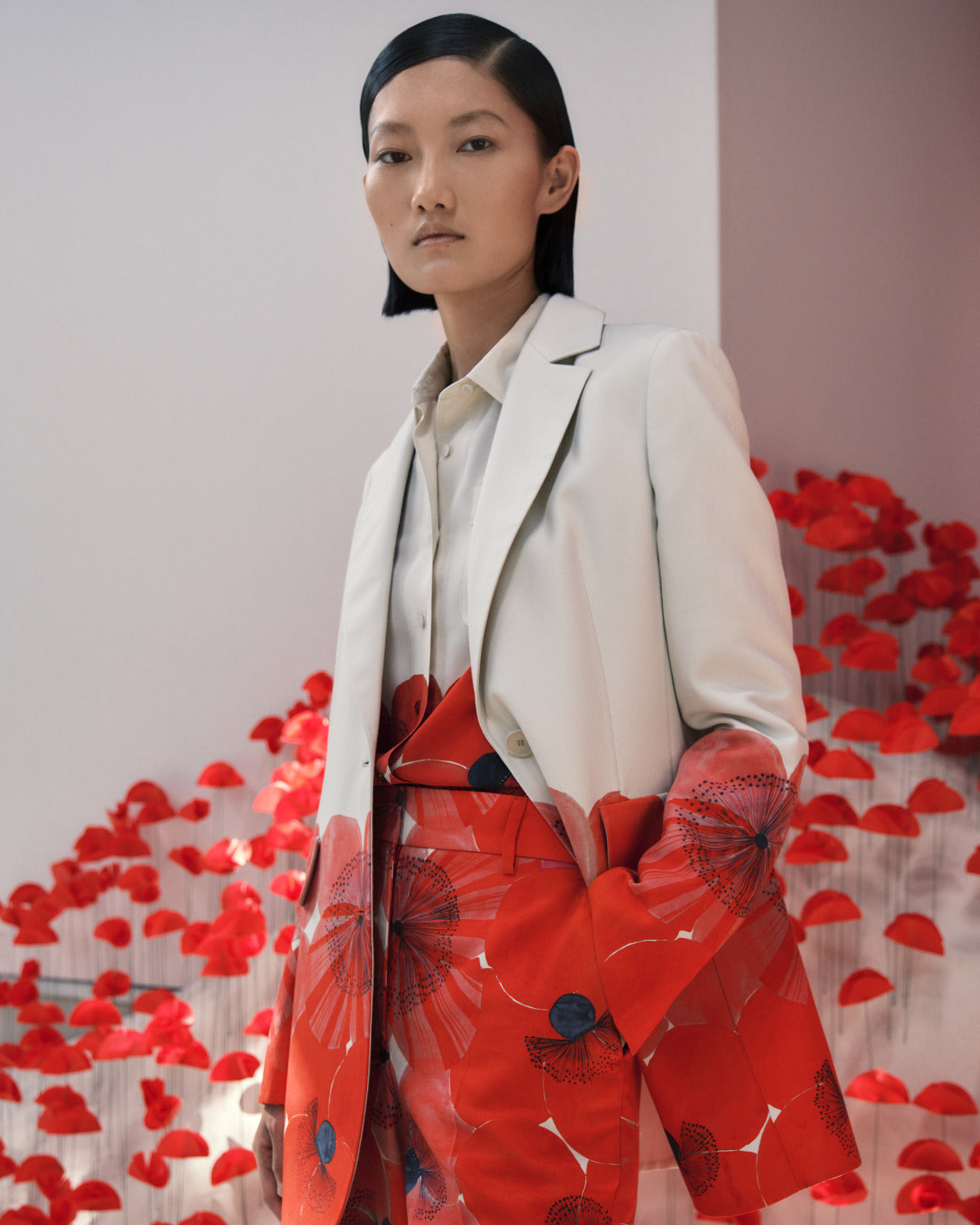 Ein asiatisches Model posiert in einem eleganten Hosenanzug mit roten Poppy Blumen-Druck von Akris