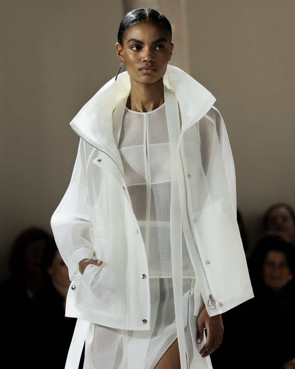 A model walkin on the runway in Paris, wearing a white sheer outfit by Akris
