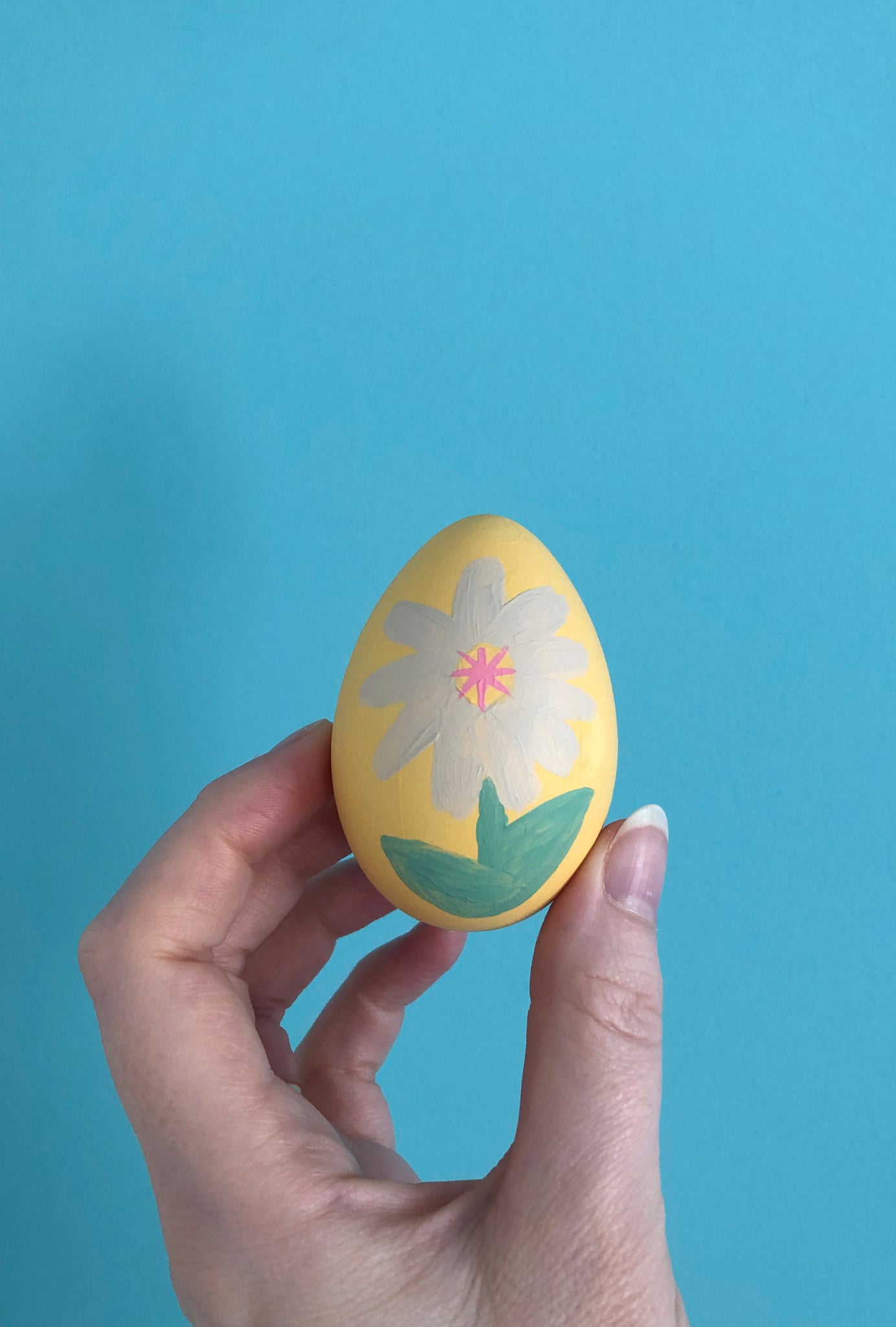 Finished painted daisy on Easter egg crafts for kids with blue background