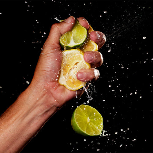 Lemon and lime being crushed in someones hand
