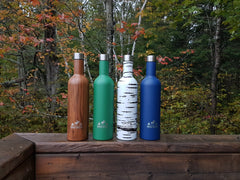 Botellas Woodland, Forest, Birch y Navy Wellington alineadas sobre una barandilla de madera.