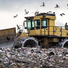 Imagen del vertedero y una gran máquina empujando la basura.