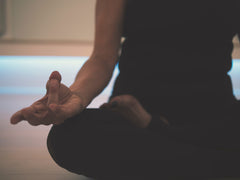 A woman sitting cross legged and meditating.