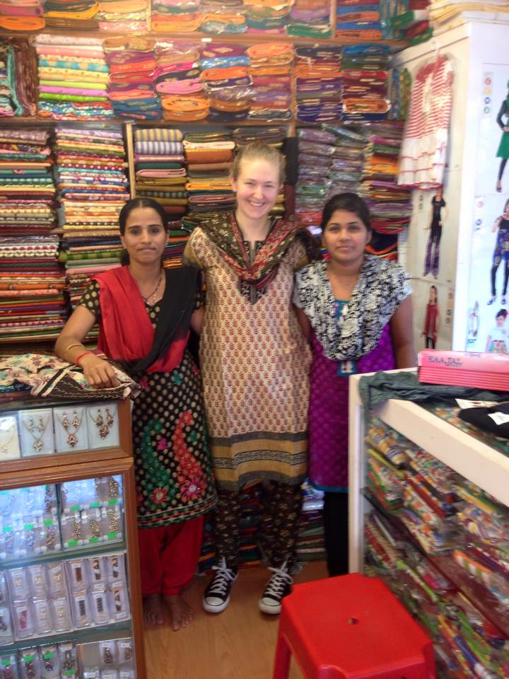 Three women smiling in front of shelves of fabric