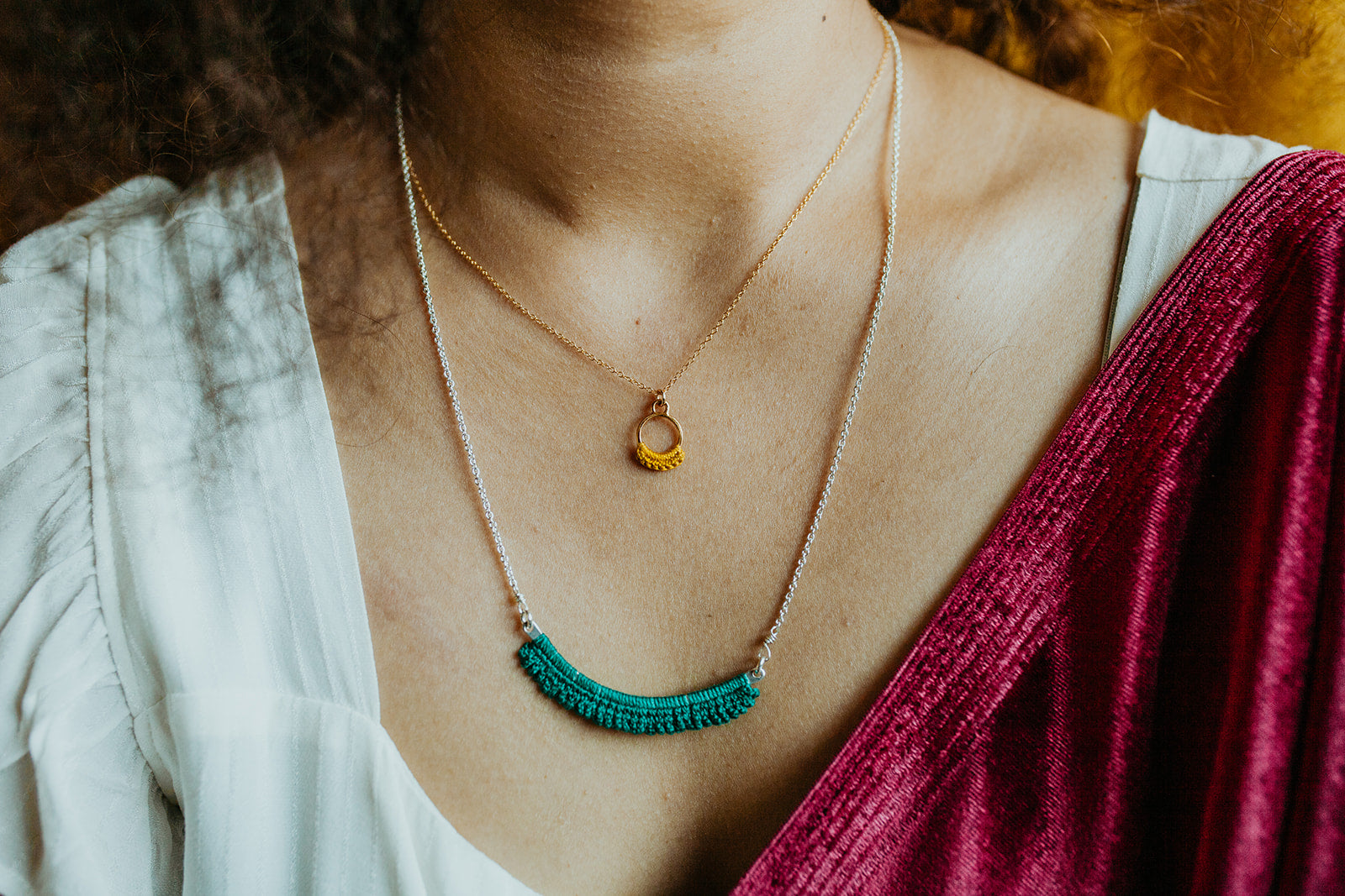 Close up view of someone's chest focusing on two layered necklaces