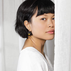 Woman glancing over her shoulder wearing a metal earring with hand-crocheted lace detailing