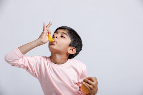 Little boy eating a slice of mango