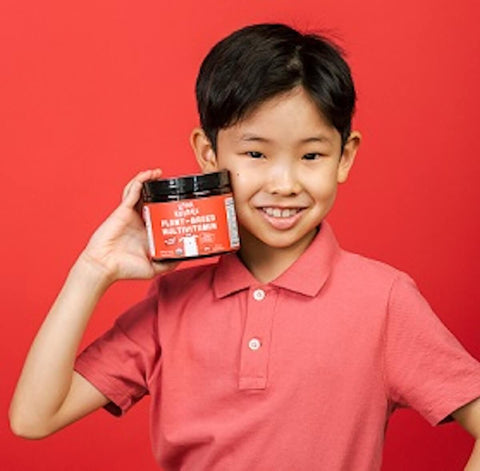 Kid holding a Llama Naturals Plant-Based Multivitamins for Kids jar