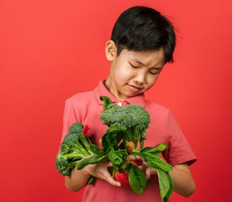 Gut health for kids: little boy holding vegetables