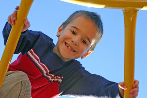 Calcium for kids: little boy smiling while playing at a playground