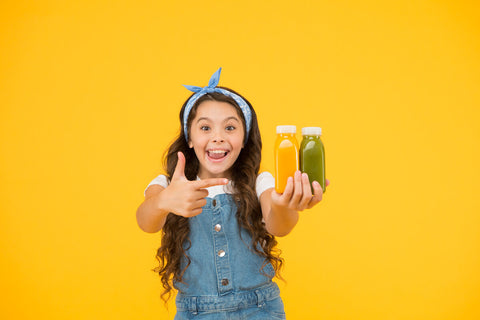 Vitamin B6 for kids: happy girl holding 2 bottles of juice