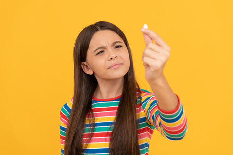 Can kids take melatonin: Girl holding a capsule