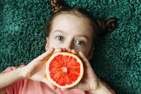 Vitamin C for kids: girl holding a sliced orange
