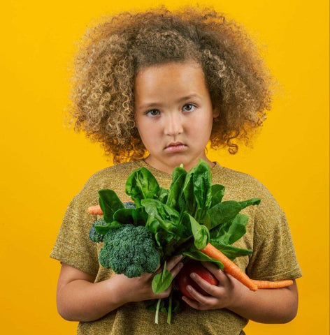 Electrolytes for kids: sad girl holding vegetables