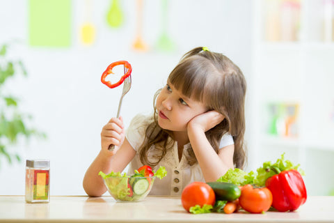 Vitamins for picky eaters: little girl holding up a slice of bell pepper