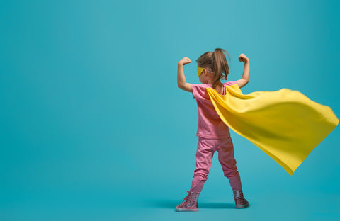 Immune boosters for kids: little girl as a superhero, wearing a yellow cape