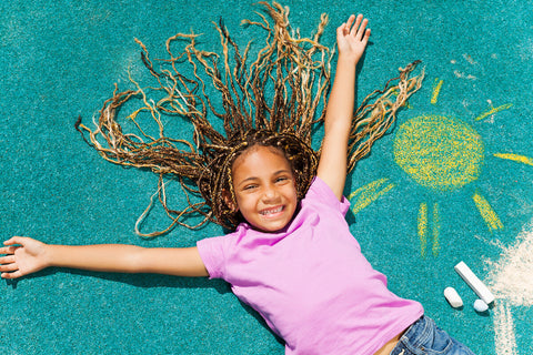 Vitamin D for kids: happy little girl lying on the floor that has a chalk drawing of the sun