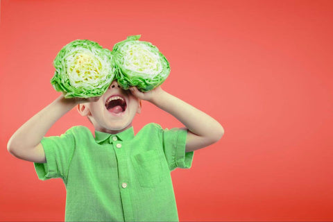 Vitamin K for kids: happy kid holding a sliced cabbage