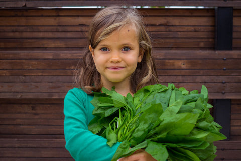 riboflavin for kids: little girl holding leafy greens