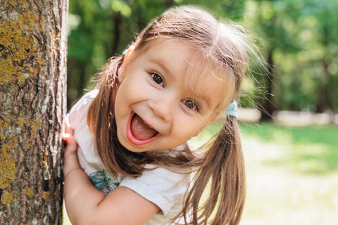 Biotin for kids: happy, little girl standing by a tree