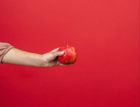 Best vitamins for teenagers: kid's arm holding an apple