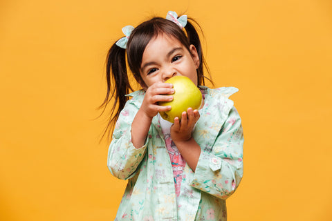 Vitamin A for kids: little girl biting into a fruit