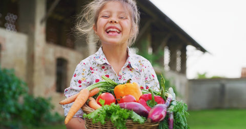 Best multivitamin for kids: little girl carrying basket of fresh vegetables