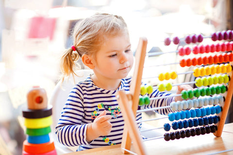 Omega 3 for kids: little girl playing with a colorful abacus