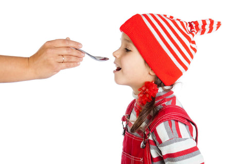 Iron supplement for kids: person feeding a little girl a spoonful of medicine