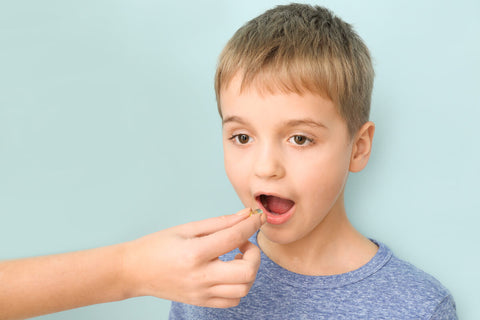 How to choose a multivitamin: person helping a boy drink his medicine