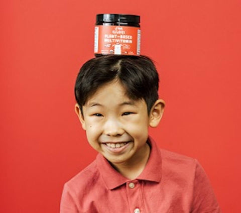 Folic acid for kids: kid with a jar of Llama Naturals on his head