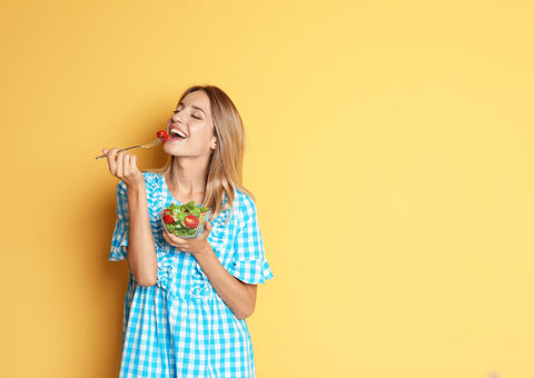 Woman happily eating a bowl of salad