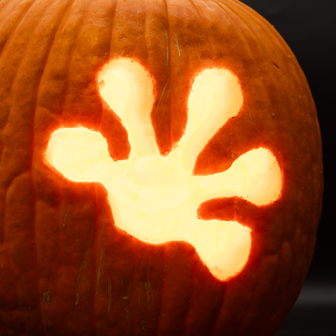 A lit-up jack-o-lantern with the Pangea gecko foot logo carved into it.