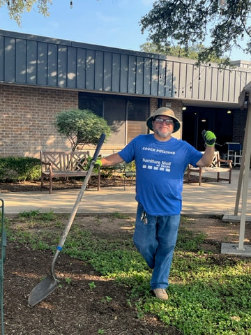 man wearing a sun hat and holding a rake. He is volunteering, and helping with the landscaping. 